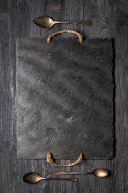 Siyah arduvaz levha ve ahşap tahta üzerinde üç vintage kaşık. Üstten görünüm, kopya alanı, dikey kompozisyon