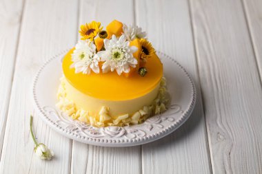 Çiçek ve beyaz ahşap zemin üzerinde taze mango adet ile sırlı Mango cheesecake