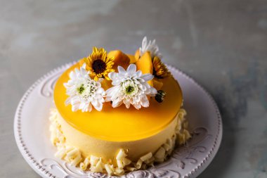 Çiçek ve gri arka plan üzerinde yuvarlak plaka üzerinde taze mango adet ile sırlı Mango cheesecake  