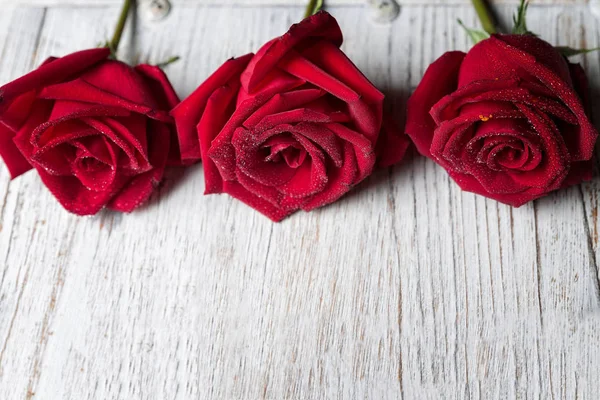 Tres rosas rojas sobre fondo de madera claro con espacio para copiar, superior — Foto de Stock