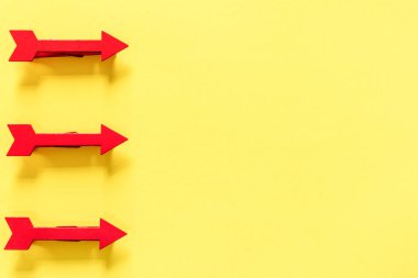 Parlak sarı arka plan üzerinde üç kırmızı ok, üst görünüm 
