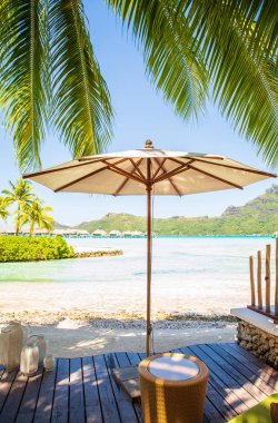 White umbrella on wooden decking with summer view of sunny beach