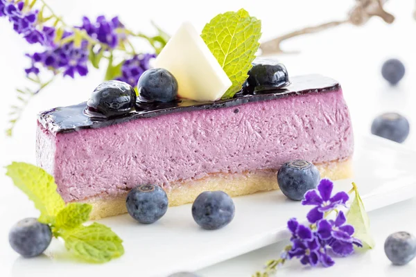 Slice of blueberry mousse cake with mint garnish and fresh berri — Stock Photo, Image