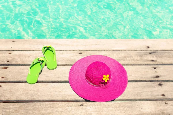 Stor rosa solhatt och sandal på trädäck vid havet — Stockfoto