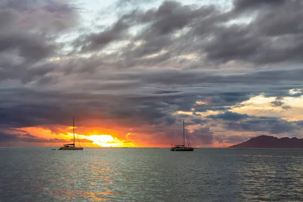 Dos veleros sobre nubes oscuras fondo y puesta de sol naranja — Foto de Stock