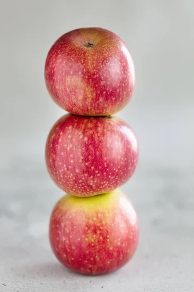 Stapel von drei Äpfeln auf hellem Hintergrund, vertikale Zusammensetzung — Stockfoto