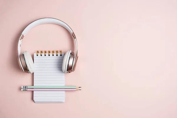 Auriculares rosa, bloc de notas en blanco y lápices sobre fondo rosa, vista superior — Foto de Stock