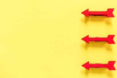 Parlak sarı arka plan üzerinde üç kırmızı ok, üst görünüm 