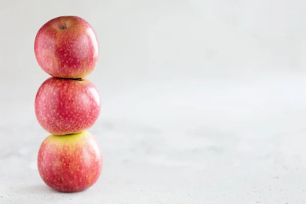 Pila di tre mele su sfondo grigio chiaro con spazio di copia — Foto Stock