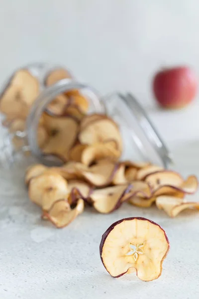 Getrocknete Äpfel Chips im Glas auf hellem Hintergrund, vertikale Zusammensetzung - Bild — Stockfoto