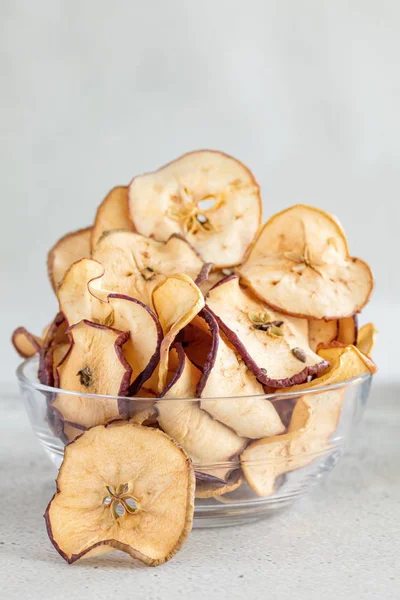 Hipped Trockenäpfel Chips in Glasschale auf hellem Hintergrund, vertikale Zusammensetzung, vetische Zusammensetzung — Stockfoto