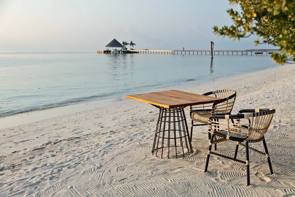 Elegante mesa y dos sillas en la playa de arena, fondo de vacaciones románticas — Foto de Stock