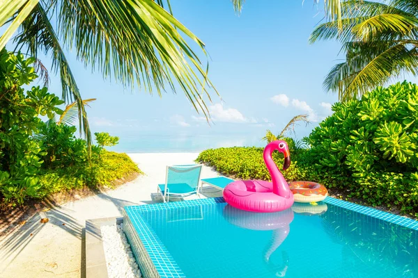 Obří růžové nafuatelné labutě s modrou bazénem v laxní tropické vile. Koncepce letní dovolené — Stock fotografie