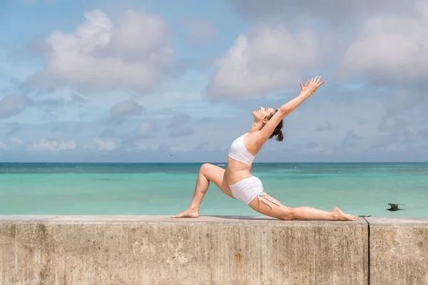 Beyaz kıyafetli beyaz kadın deniz kenarında yoga yapıyor Telifsiz Stok Imajlar