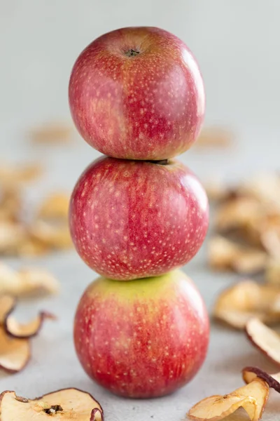 Stapel von drei frischen Äpfeln und sonnengetrockneten Apfelchips als gesunder Snack, vertikale Zusammensetzung — Stockfoto