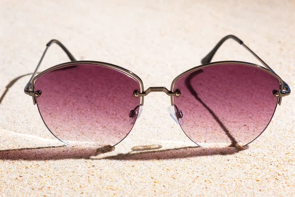 Pink Ladies fashionable sunglasses on sandy beach at sunny day