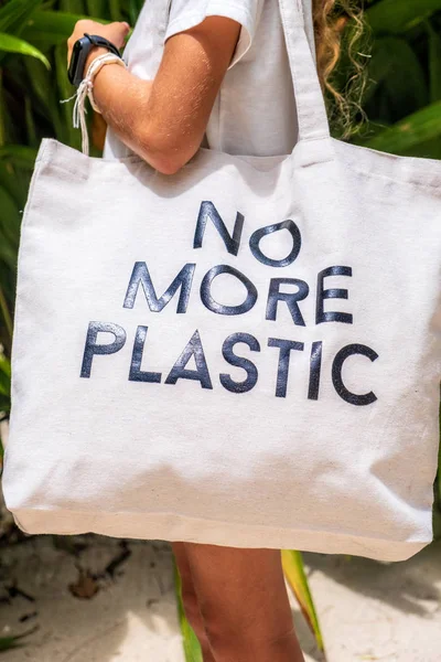 Nuori tyttö valkoinen t-paita tilalla Eco laukku NO LISÄÄ PLASTIC trooppisella taustalla — kuvapankkivalokuva