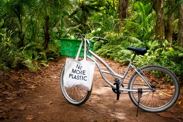 Eco bag NO LEBIH PLASTIC dalam keranjang hijau sepeda kesepian tua di tanah jalan pedesaan di tengah hutan tropis — Stok Foto
