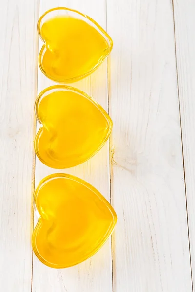 Jalea de limón amarillo en vidrio en forma de corazón sobre fondo de madera blanca, vista superior — Foto de Stock