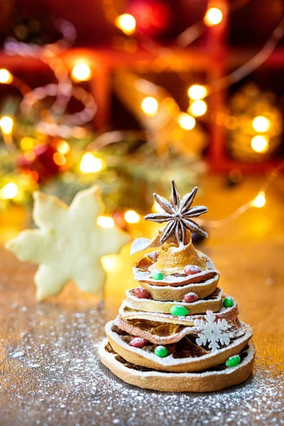 Choinka wykonana z suszonych plasterków pomarańczy i gwiazdy anyżu, z świątecznym światłem i ciasteczkami na tle, kompozycja pionowa — Zdjęcie stockowe