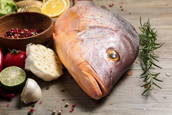新鲜的生红鱼与香料，草药和蔬菜在木制背景烹饪. — 图库照片