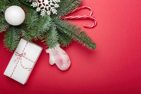 Kerst decoratie op verse en verse brunch van kerstboom op rode achtergrond, platte lay met Kopieer ruimte — Stockfoto