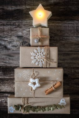 Yaratıcı bir şekilde paketlenmiş ve süslenmiş Noel hediyeleri ahşap zemin üzerinde Noel ağacı şeklinde, dikey kompozisyon