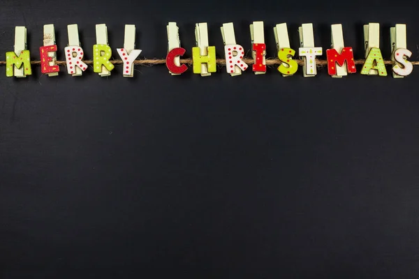 Houten clips met Merry Christmas sighn op zwarte achtergrond met kopie ruimte — Stockfoto