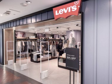 Singapur, Singapur - 30 Nisan 2025: Bir Levis mağazası, yüzde 50 indirimli özel etkinlik tabelasıyla ince, gevşek ve inceltilmiş seçenekler de dahil olmak üzere çeşitli giyim tarzlarını sergiliyor.