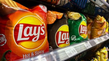 Penang, Malezya - 7 Temmuz 2025: Acılı ve Baharatlı olmak üzere çeşitli çeşnilerde Lay 'in patates cipsi paketleri bir marketin rafında sergilendi..