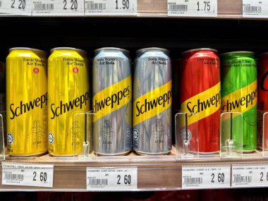 Penang, Malezya - 7 Temmuz 2025: bir mağaza rafında farklı türler için RM 2.60, RM 1.75 ve RM 2.90 fiyatlarına sarı, gümüş, kırmızı ve yeşil renkli Schweppes kutuları bulunur..