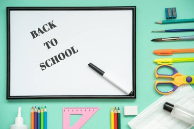 Okula yeni bir gerçeklikte, bir tıbbi maske, bir dezenfektan, bir kırtasiye malzemesi: kalemler, kalem, fırça, tutkal, makas, cetvel. Okula mesaj at, düz uzan.. 