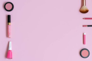 Pembe arka planda boş fotokopi alanı olan kozmetik ürünler. Makyaj, pastel renkli arka planlı cilt bakımı konsepti. Allık, dudak parlatıcısı, dudak kalemi, göz farı, oje, parfüm ve fırça..