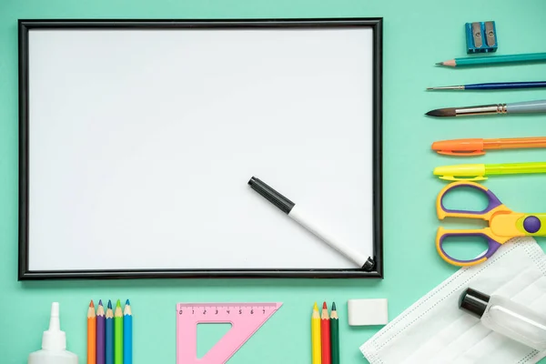 Okula yeni bir gerçeklikte dönmek, bir tıbbi maske, bir dezenfektan, bir kağıt: kalemler, makas, bir cetvel. konunun üzerine yat okula geri dön.