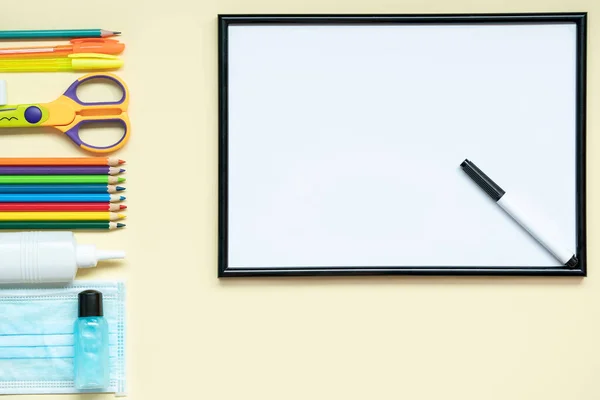 Okula yeni bir gerçeklikte dönmek, bir tıbbi maske, bir dezenfektan, kağıt: kalemler, kalem, makas, yapıştırıcı. konunun üzerine yat okula geri dön.