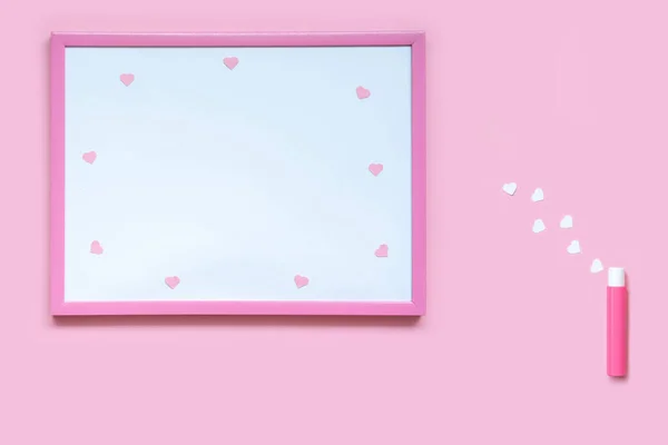 Kağıt kalplerle süslenmiş şık bir parfüm şişesi. Pembe arka planda kızlar için aksesuarlar: pembe çerçeveli kalpler, kağıt kalpler pembe ve beyaz. parfüm ve koku kavramı. 