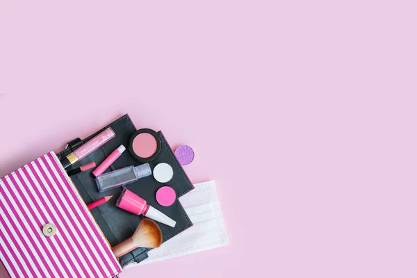 Makyaj için makyaj malzemesi olan kadınlar pembe el çantası: göz farı, dudak parlatıcısı, tırnak cilası, allık, fırça, maske ve dezenfektan, 2020 yazı, pembe arka planda pembe kozmetik ürünleri.