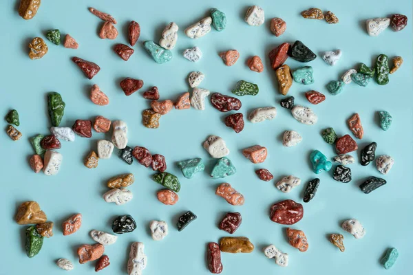 Dekorasyon ve el yapımı işler için renkli çakıl taşları. Renkli taş, mavi arkaplanda doku. Hepimizin farklı olduğunu kabul et..