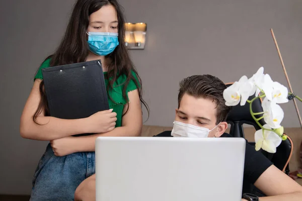Kız ve erkek bir salgın sırasında birlikte bir proje hazırlıyorlar, maskenin yüzünde. Okula dönüş kavramı. Öğrenciler takım çalışması. Evde özel ders veriyorum. Dizüstü bilgisayar tamir sihirbazı, yazılım yükleme sihirbazı