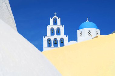 Pyrgos, Santorini, Yunanistan, güzel cityscape ile çan kulesi ve mavi kilise kubbe, duvarlar, arka plan ve sarı ön şaşırtıcı mavi gökyüzünde badanalı 