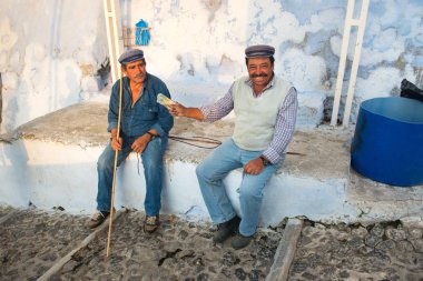 Santorini, Yunanistan - 19 Ekim, 2018: Fira, Santorini, turist ile eşek kuralları iki adam sheperds bir dinlenme yaşıyorsanız, işlerini zavallı hayvanların çok kötü niyetli