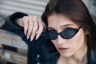 deri ceketli genç kız sigara içiyor, rock tarzı, arsız ve sevimli kız sokak poz tarzı, rock punk yaşam tarzı