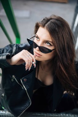 deri ceketli genç kız sigara içiyor, rock tarzı, arsız ve sevimli kız sokak poz tarzı, rock punk yaşam tarzı