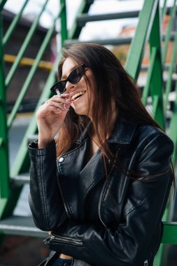 deri ceketli genç kız sigara içiyor, rock tarzı, arsız ve sevimli kız sokak poz tarzı, rock punk yaşam tarzı