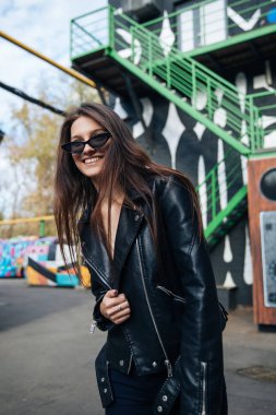 deri ceketli genç kız sigara içiyor, rock tarzı, arsız ve sevimli kız sokak poz tarzı, rock punk yaşam tarzı