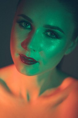 Güzel bir genç kızın yüzüne çarpıcı bir makyaj, güzellik makyajı, yüzünde yağ ve kırmızı renkli parlaklıklar öncelikli olacak.