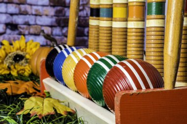 izole eski ahşap kroket sonbahar ile yeşil çimenlerin üzerinde renkli çizgili topları ile ayarla sarı ayçiçeği ve turuncu tuğla duvar arka plan ile kabak bırakır