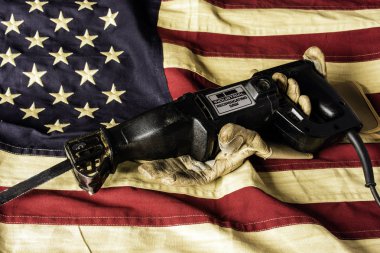 Endüstriyel pistonlu çay leke pamuk Amerikan bayrağı üzerinde yıpranmış deri çalışma eldivenleri tarafından tutulan testere
