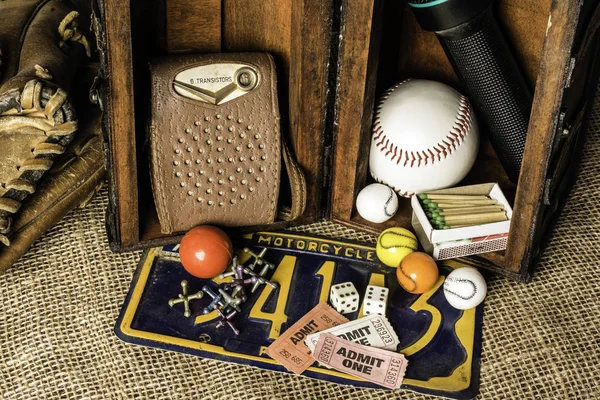 opened wood chest showing young boys treasures baseball transistor radio matches  bubble gum baseball glove jacks dice tickets motorcycle license plate flashlight on burlap background