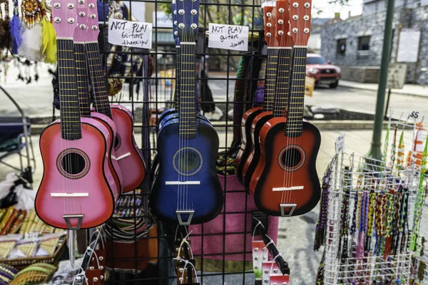 colorful guitars hanging in booth at street festival in small town marked with signs saying do not play guitars